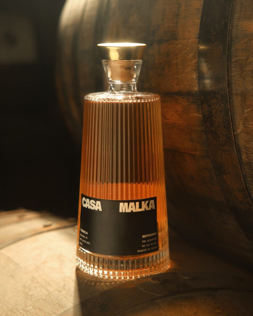 Casa Malka Reposado Tequila bottle sitting on a barrel, emphasizing traditional aging process